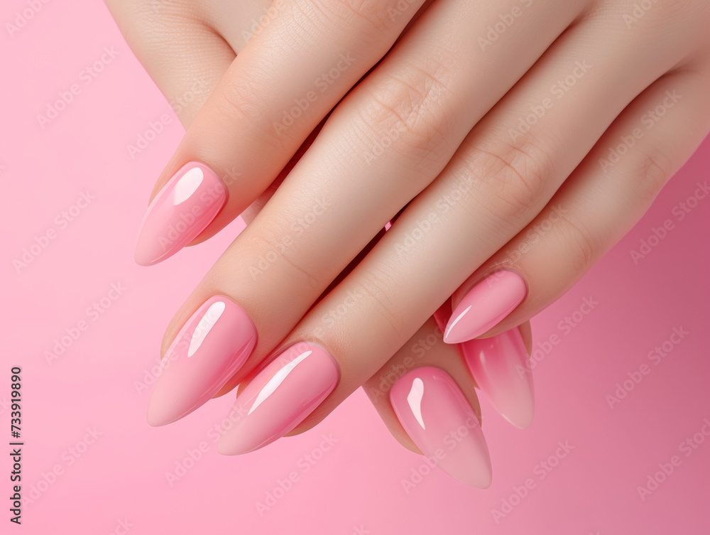 Close-up of a woman's hands with long almond-shaped nails in a glossy pink ombre manicure, set against a pink background Close-up of a woman's hands with long almond-shaped nails in a glossy pink ombre manicure, set against a pink background