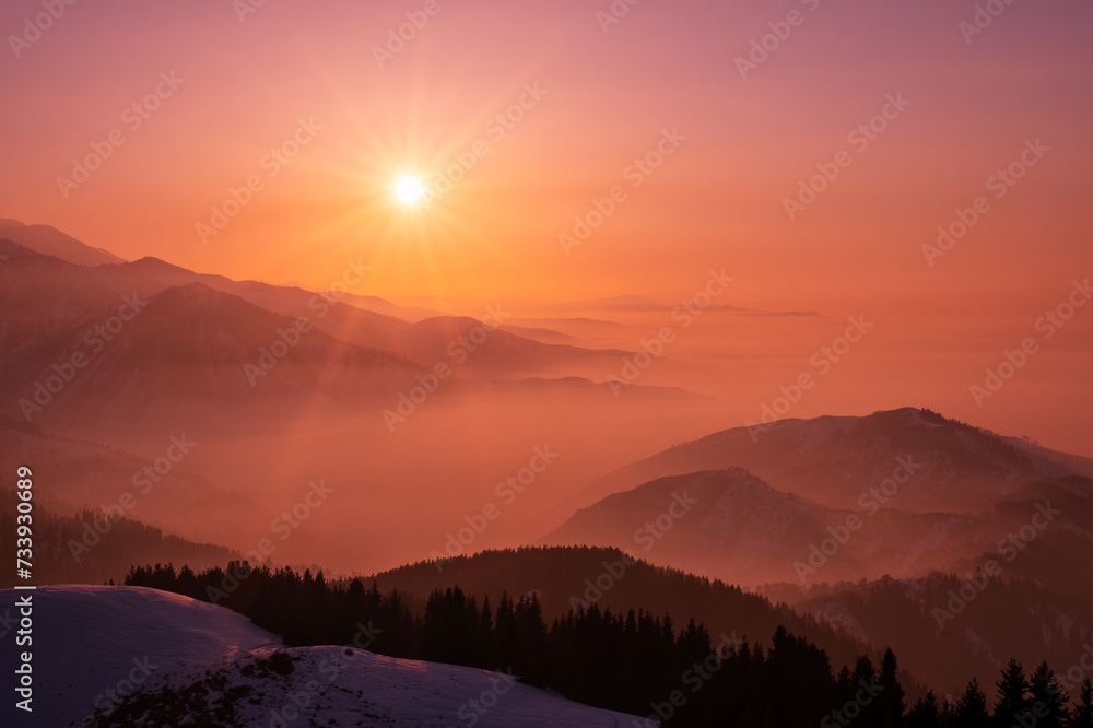 Magical view of a mountain valley shrouded in a light haze at sunset; magical atmosphere of a sunset in the highlands