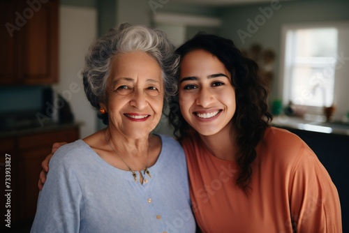 Happy mexican american elderly mom and young daughter woman posing at home, looking at camera with toothy smiles, laughing, hugging, enjoying warm family relationship, bonding. Head shot portrait 
