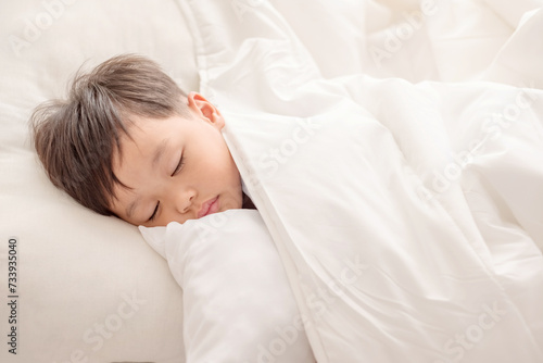 Adorable little boy sleeping in white bed. people, children, rest and comfort concept. Soft focus. Copy space.