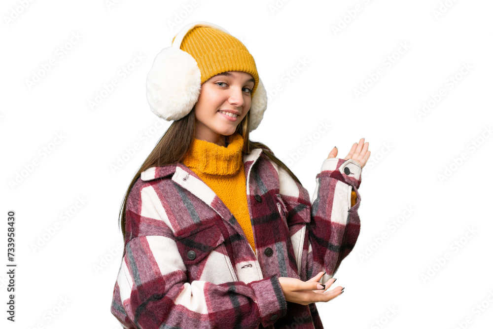 Teenager caucasian girl wearing winter muffs over isolated background extending hands to the side for inviting to come