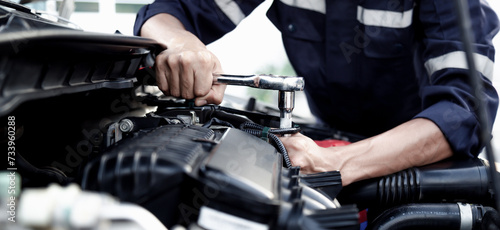 Mechanic are using the wrench to repair and maintenance auto engine at car repair shop,Car auto services and maintenance check concept.