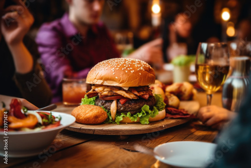 People enjoying a delicious meal, burgers, onion rings and french fries while dining out