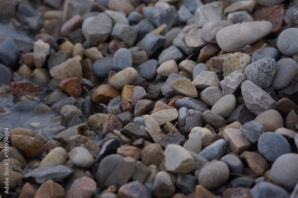 Macro of pile of multicoloured rocks with small puddle Macro of pile of multicoloured rocks with small puddle