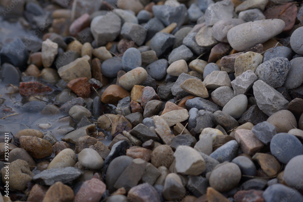 Macro of pile of multicoloured rocks with small puddle Macro of pile of multicoloured rocks with small puddle