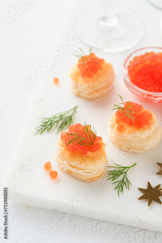 Salmon red caviar toast. Christmas canape or toast with red caviar on white plate on light background. Idea to xmas snack. Gourmet food. Texture of caviar. Seafood.