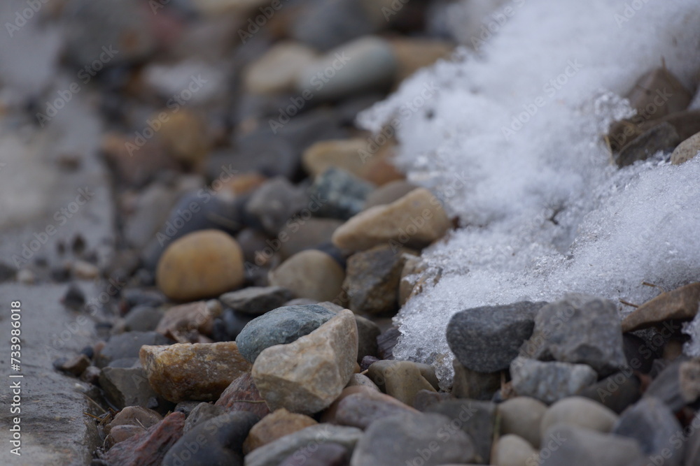 Multicoloured pebbles with patch of snow on it, macro Multicoloured pebbles with patch of snow on it, macro
