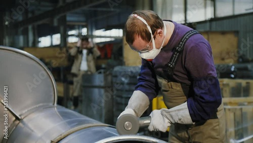 Industrial worker in glasses processing metal with grinding tool