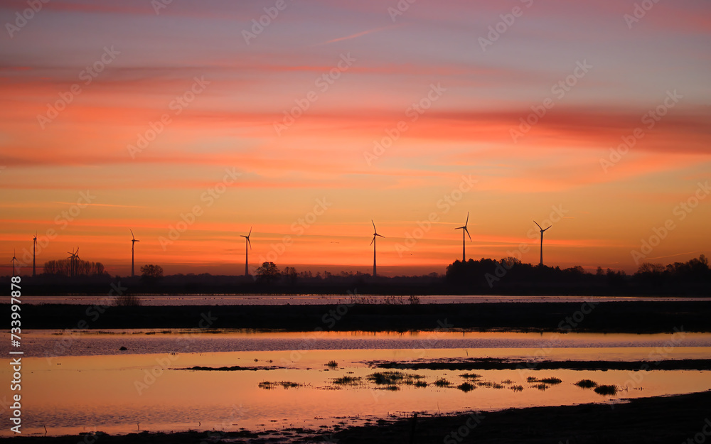 An image of windturbine in the field at sunset.