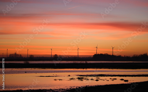 An image of windturbine in the field at sunset.