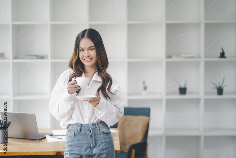 Beautiful young concentrated business woman wearing shirt using laptop while standing in modern workspace