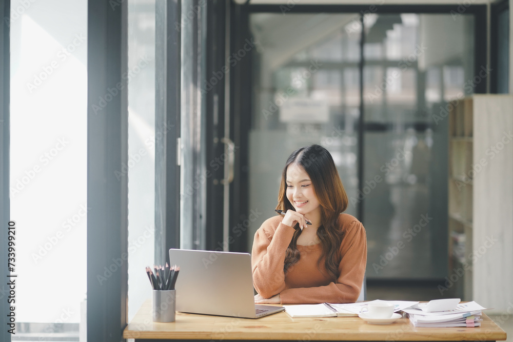 Beautiful young concentrated business woman wearing shirt using laptop while standing in modern workspace Beautiful young concentrated business woman wearing shirt using laptop while standing in modern workspace