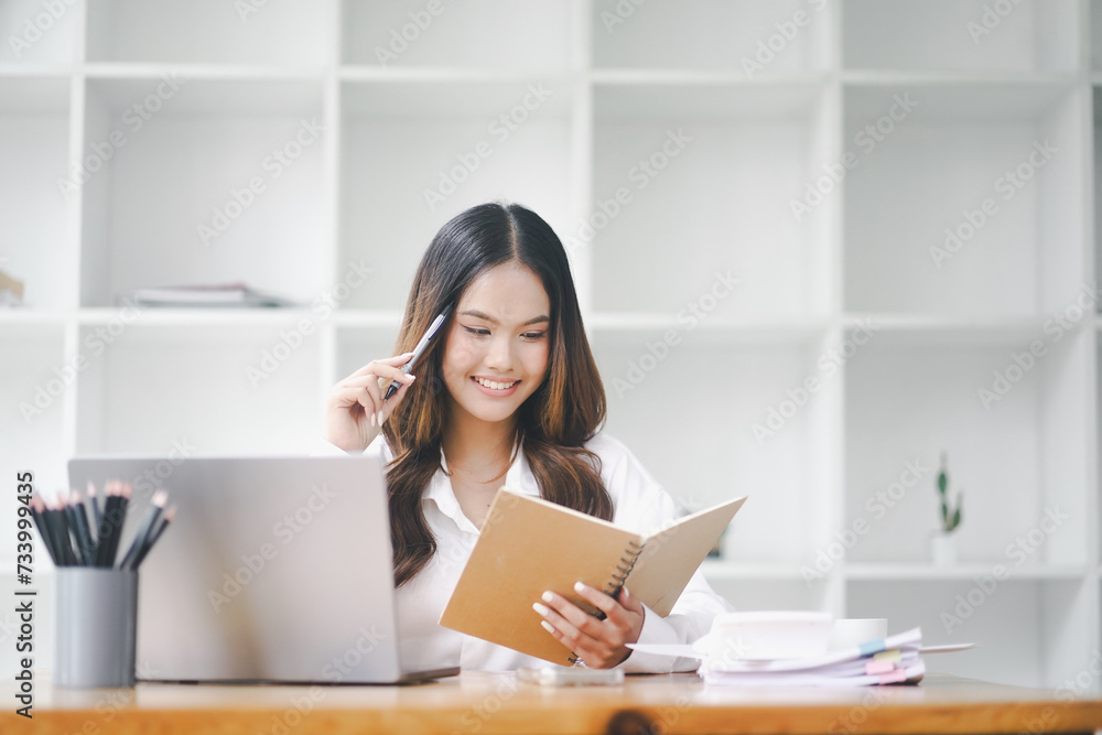 Beautiful young concentrated business woman wearing shirt using laptop while standing in modern workspace Beautiful young concentrated business woman wearing shirt using laptop while standing in modern workspace