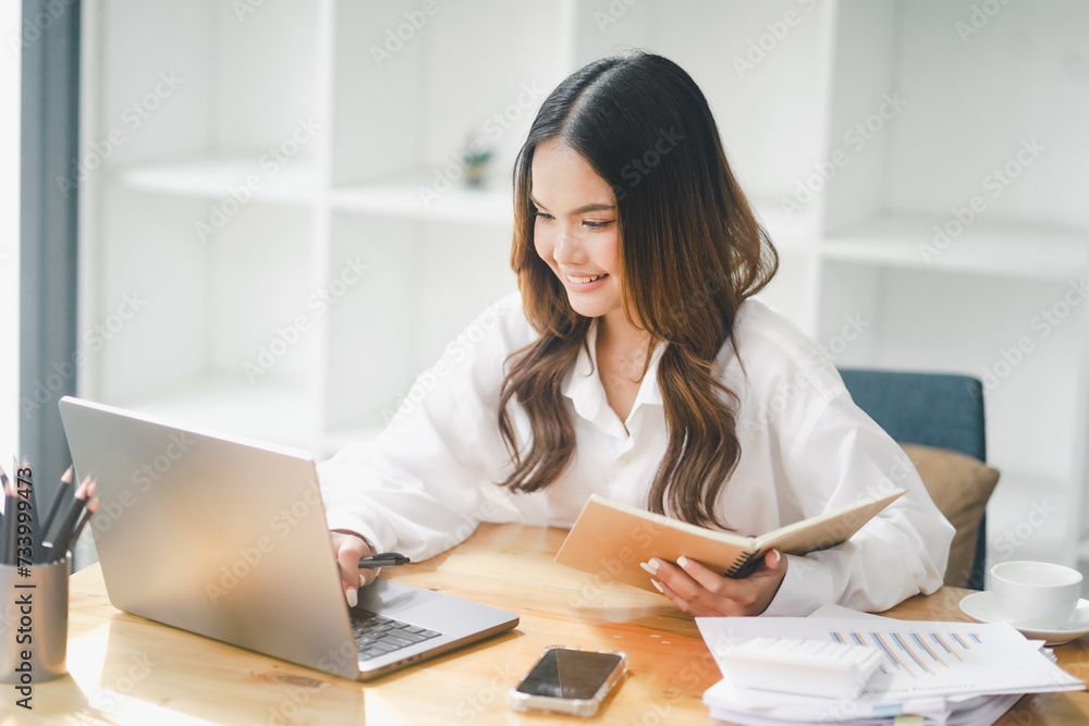 Beautiful young concentrated business woman wearing shirt using laptop while standing in modern workspace Beautiful young concentrated business woman wearing shirt using laptop while standing in modern workspace