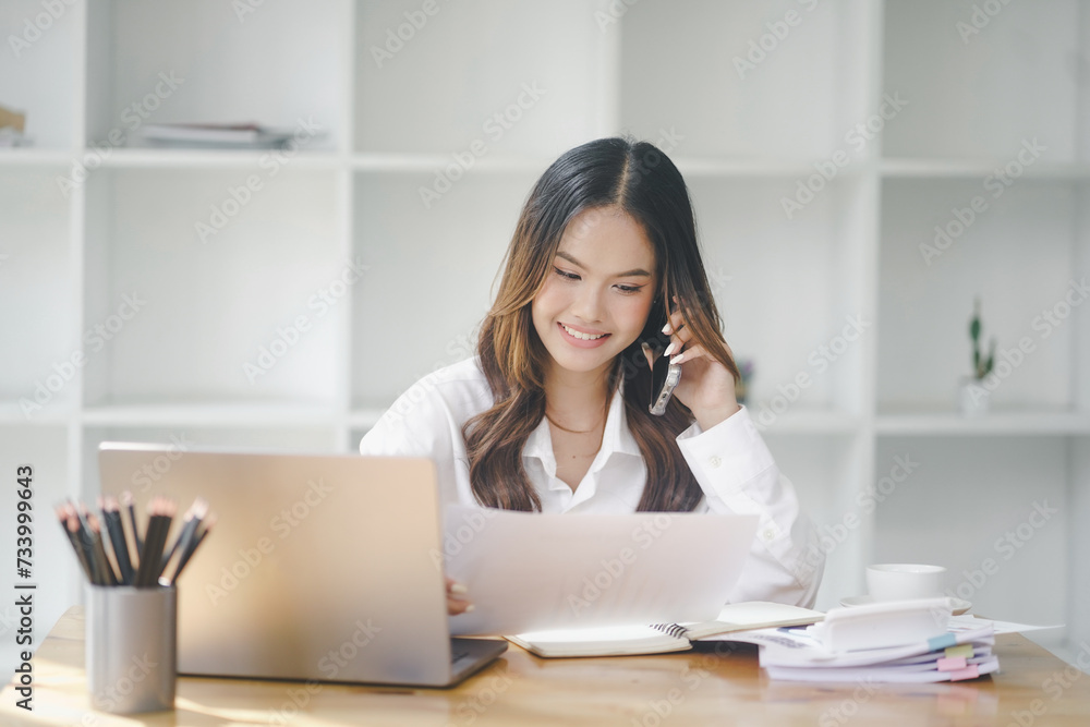 Beautiful young concentrated business woman wearing shirt using laptop while standing in modern workspace Beautiful young concentrated business woman wearing shirt using laptop while standing in modern workspace