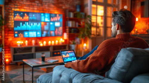 A focused man in a cozy home setting analyzing complex financial data on multiple computer screens at night.