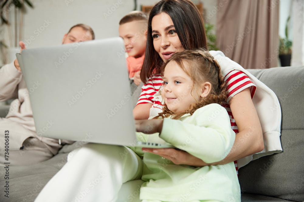 Family sitting in living room and booking tickets and hotel for their holidays. Parents and children sitting on couch in living room at home. Concept of tourism, vacation, luxury resort, relaxation. Family sitting in living room and booking tickets and hotel for their holidays. Parents and children sitting on couch in living room at home. Concept of tourism, vacation, luxury resort, relaxation.