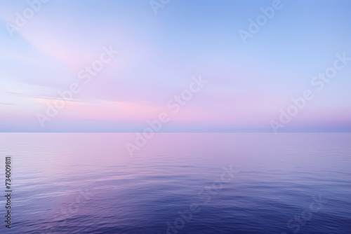 A serene seascape at dawn, featuring a gradient sky transitioning from deep blue to soft lavender, reflecting on calm waters. © Kanwal