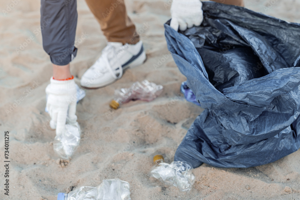 Hands of an activist picking up plastics and trash that pollutes the sea. Contamination and zero-waste way of living. Non-profit charitable organization to save the world Hands of an activist picking up plastics and trash that pollutes the sea. Contamination and zero-waste way of living. Non-profit charitable organization to save the world