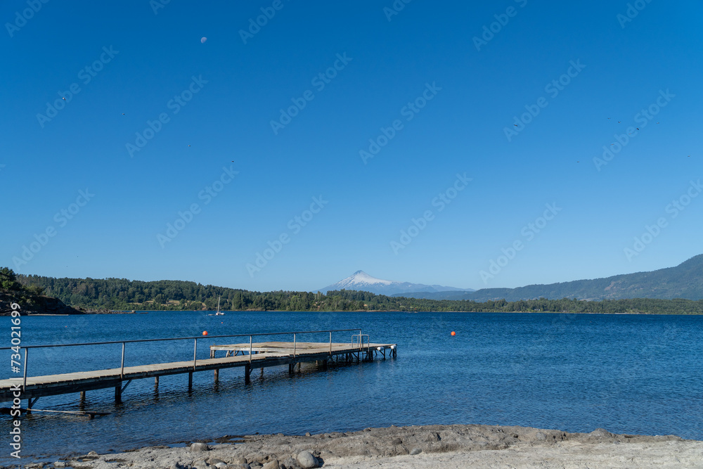 A serene summer day at a vacation lake. View of the dock with the volcano in the background.