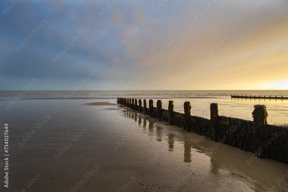 Sunset on Felpham beach on a winter evening, West Sussex, England. View of the wooden groynes.