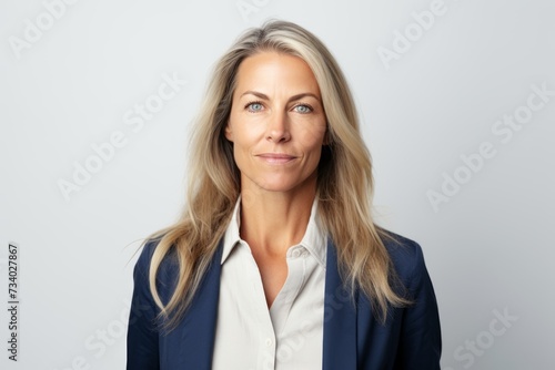 Confident businesswoman looking at camera with serious expression, over grey background