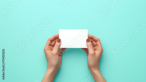Woman’s Hands holding blank paper mock up isolated on sky blue background