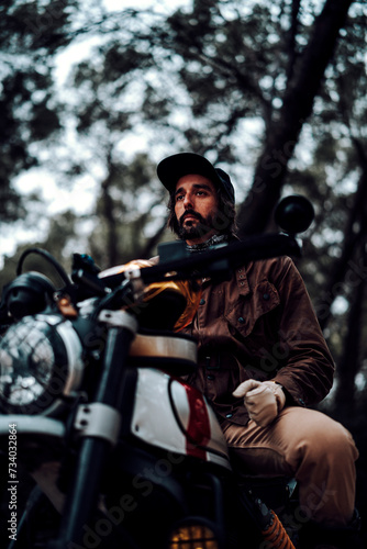 Hombre moreno con moto dentro de un bosque posando y montando por terreno silvestre