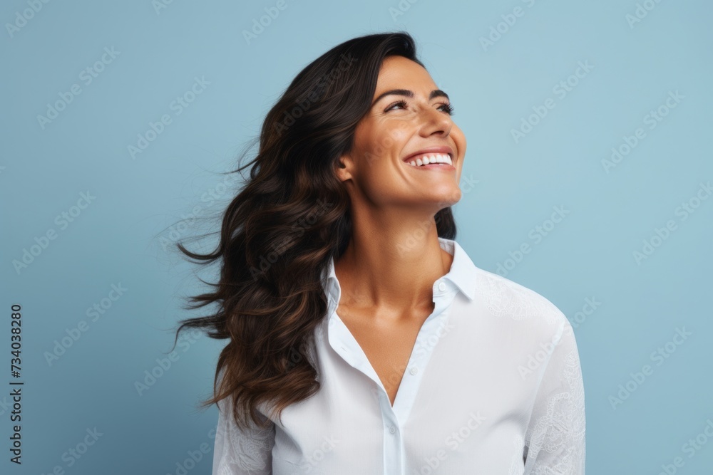 Happy smiling young brunette woman in white shirt on blue background. Happy smiling young brunette woman in white shirt on blue background.