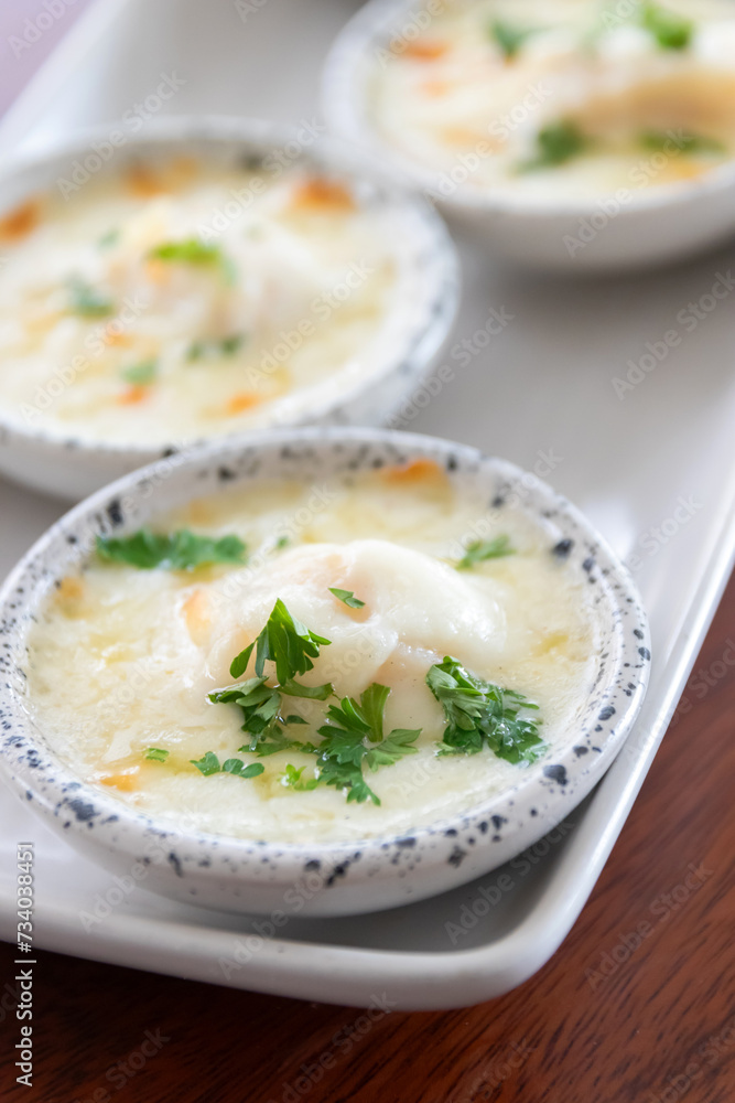 Baked scallop with cheese in mini bowl.