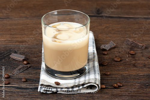 Glass with ice in original Irish cream liqueur, coffee beans and chocolate pieces.