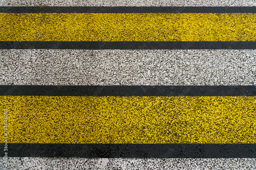 Fototapeta premium Road markings on wet asphalt. White yellow zebra for pedestrian safety. Pedestrian crossing. A copy place.