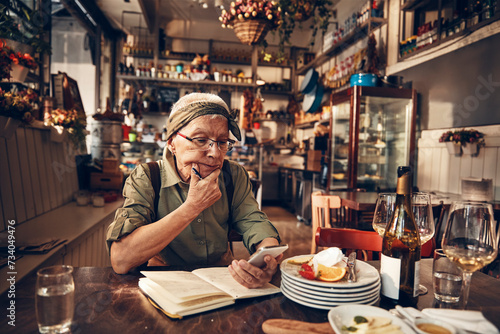 Senior waitress doing expenses at a restaurant table