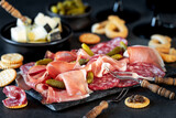 Speck and salami meat platter with pickled gherkins served with cheese, crackers and taralli