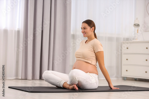 Pregnant woman doing exercises on yoga mat at home
