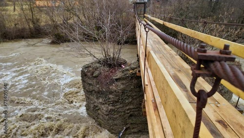 Ukraine, Carpathians, Transcarpathia, severe flooding in the mountains in winter after rains, a mass of water flows into the valleys, a menacing sight from a hanging rope bridge photo