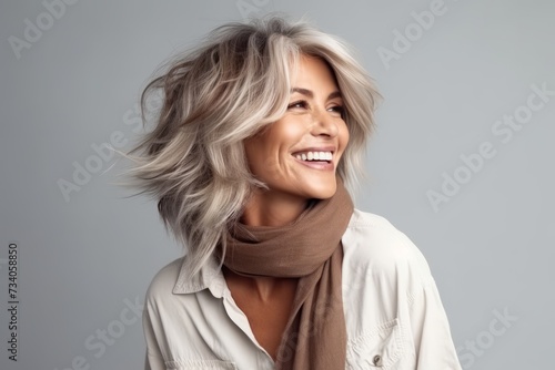 Beautiful young woman with blond hair and brown scarf on grey background
