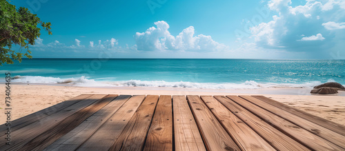 Empty wooden table or deck at the front overlooking vast sandy beach and turquoise sea or ocean water. Copy space mockup 