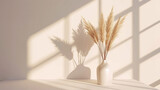Beige reeds in vase standing on white table with beautiful shadows on the wall