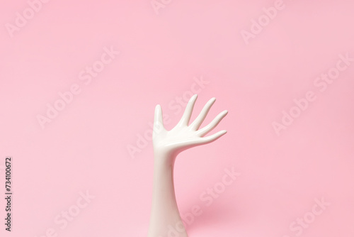 White ceramic statue hand on pink background with copy space