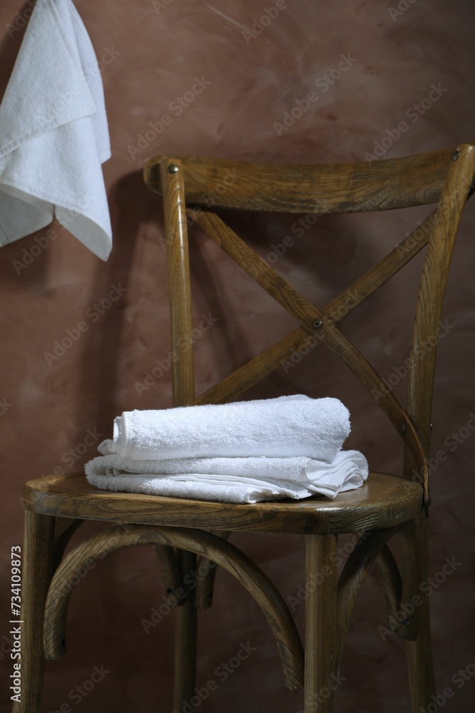White terry towels on wooden chair against brown background White terry towels on wooden chair against brown background
