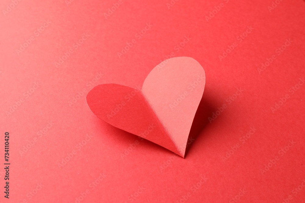 One bright paper heart on red background One bright paper heart on red background