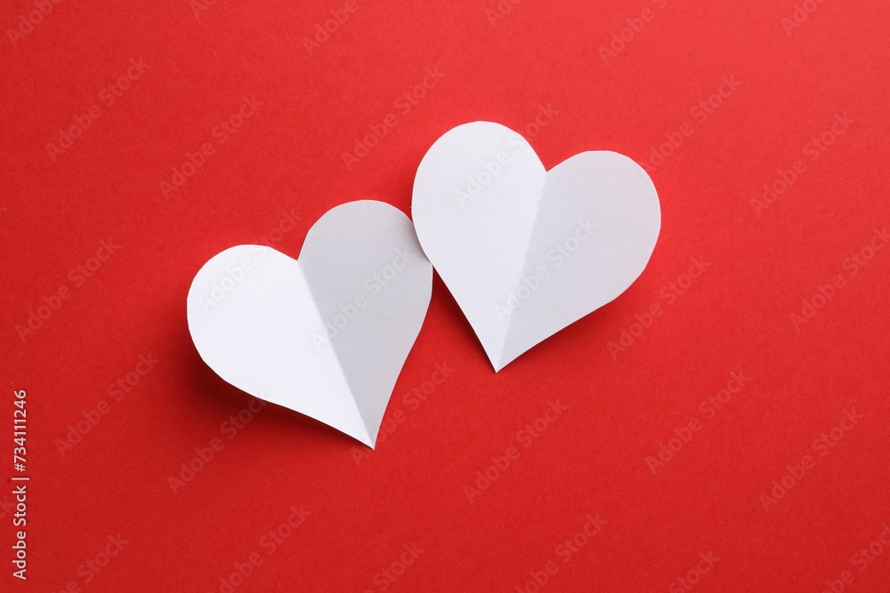 White paper hearts on red background, flat lay