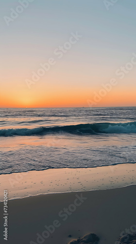 Sunset at the beach, the sun dips below the horizon on a peaceful beach, with gentle waves approaching the sandy shore