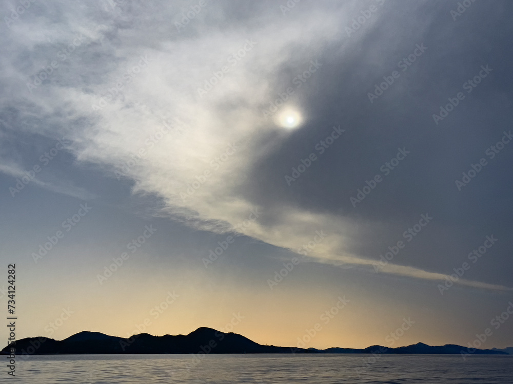 the sun is shining through a cloudy sky over the ocean