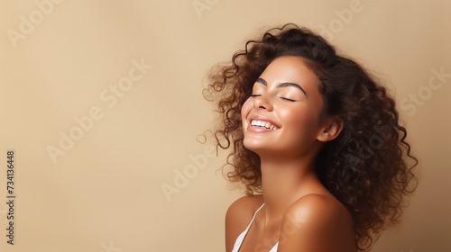 Portrait of smiling girl enjoying beauty treatment on beige background. Beautiful natural woman looking at copy space, spa and wellness concept. Carefree laughing woman with bare shoulders isolated. photo