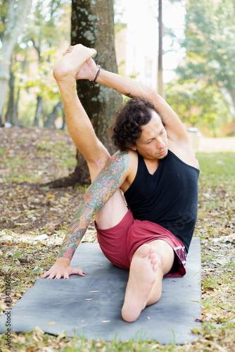 a man practicing yoga poses in the park in the middle of nature photo