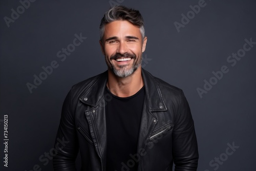 Portrait of a smiling mature man in leather jacket on grey background