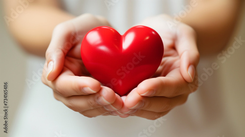 A close-up of a woman s hands holding a heart-shaped object  symbolizing love and care  against a clean