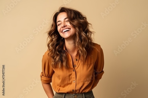 Portrait of a happy young woman laughing over beige background.
